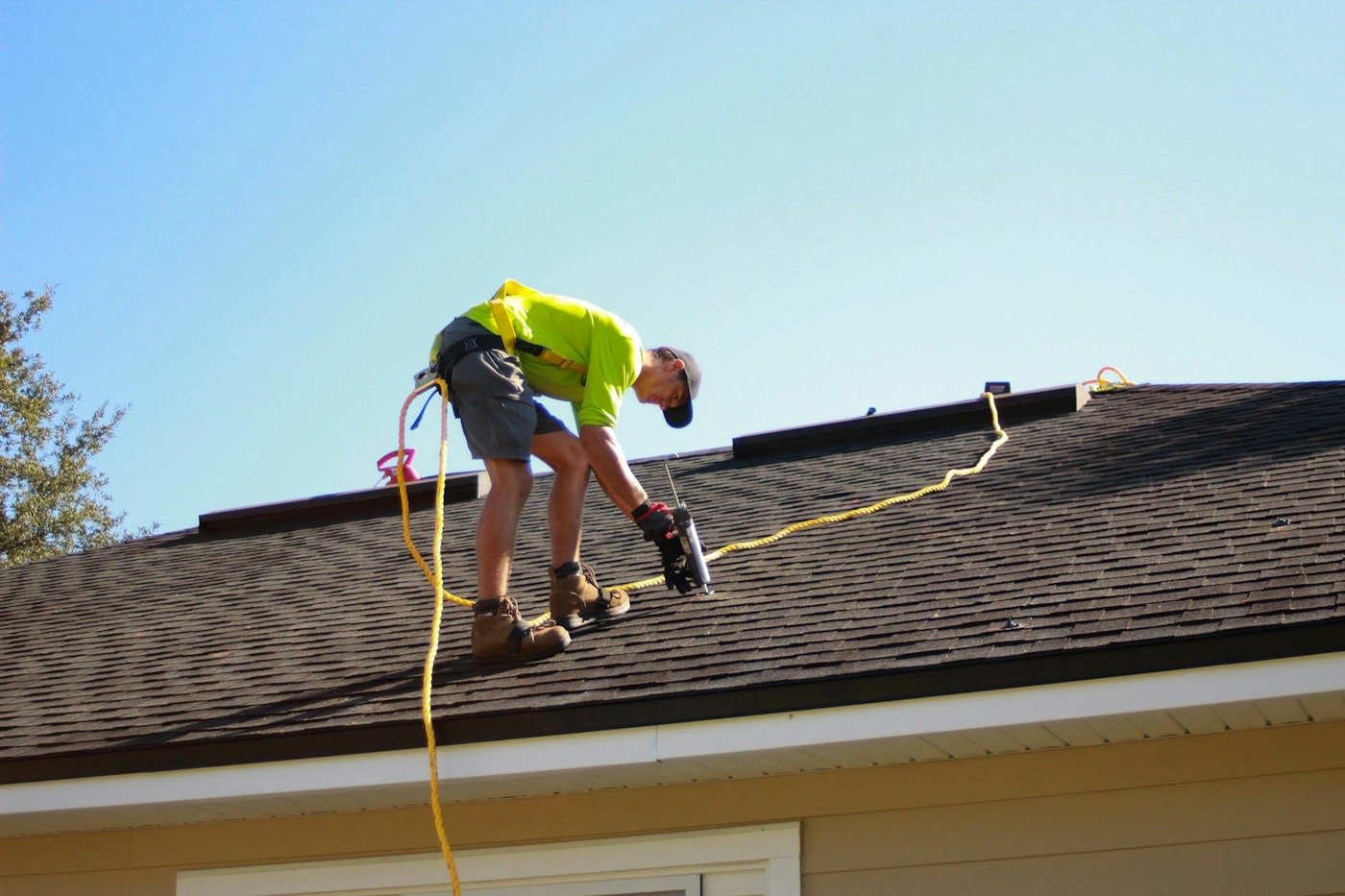 A roofer fastening shingles on a sloped roof