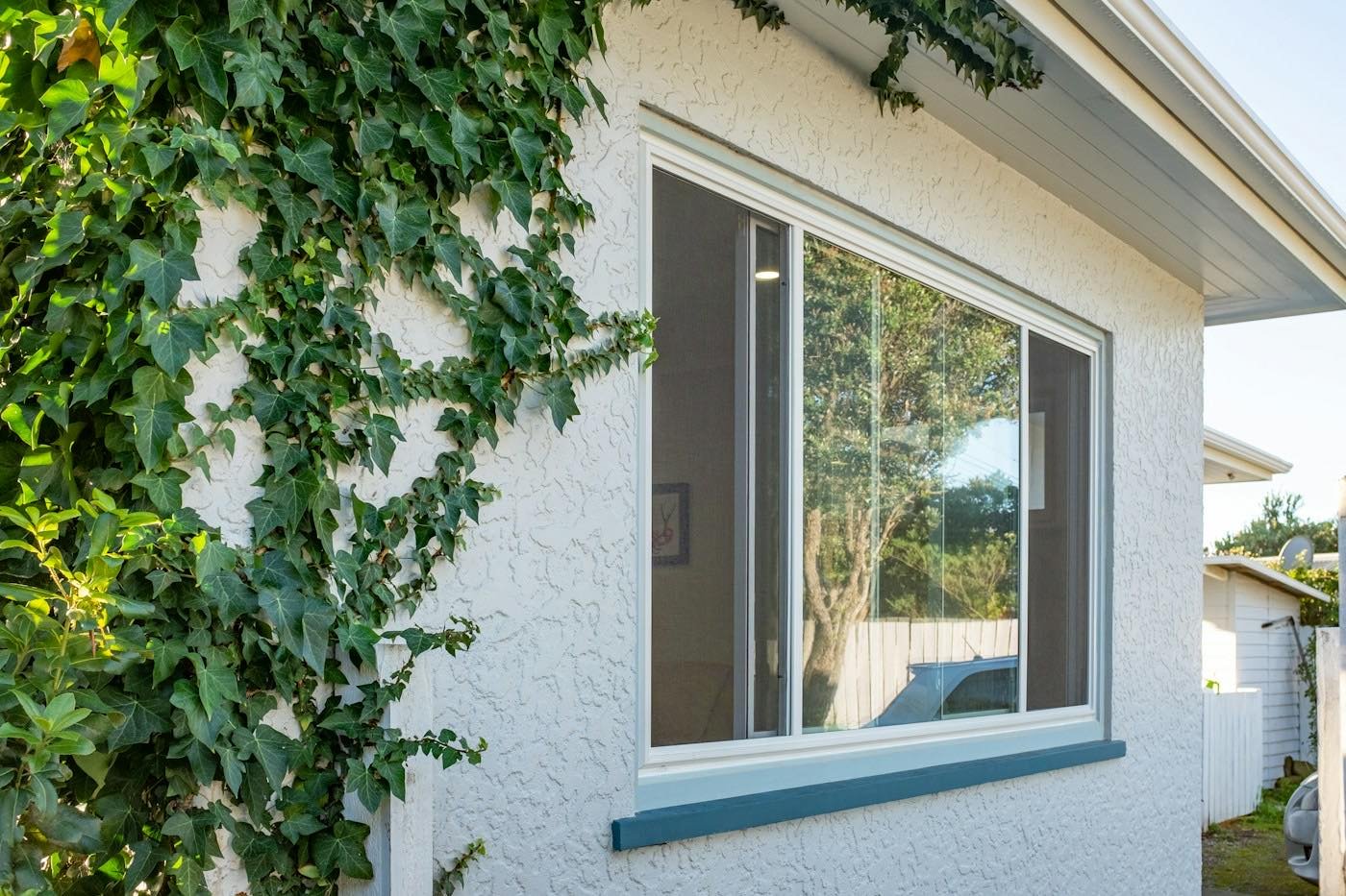 A sliding window on a house exterior with ivy