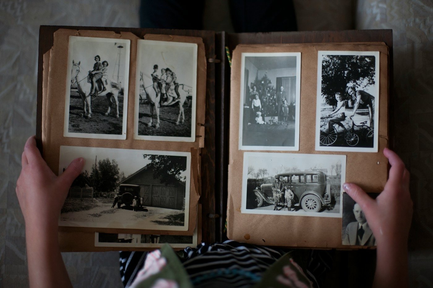 Hands holding open an old photo album of black and white photographs