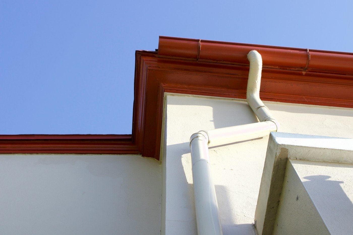 A gutter and downspout on the corner of a house
