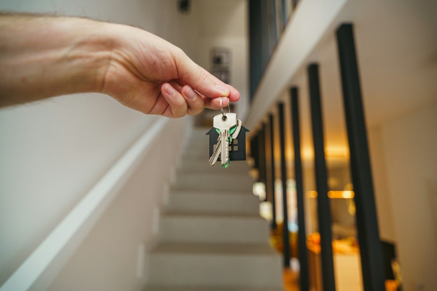 A hand holding house keys with a house shaped keychain