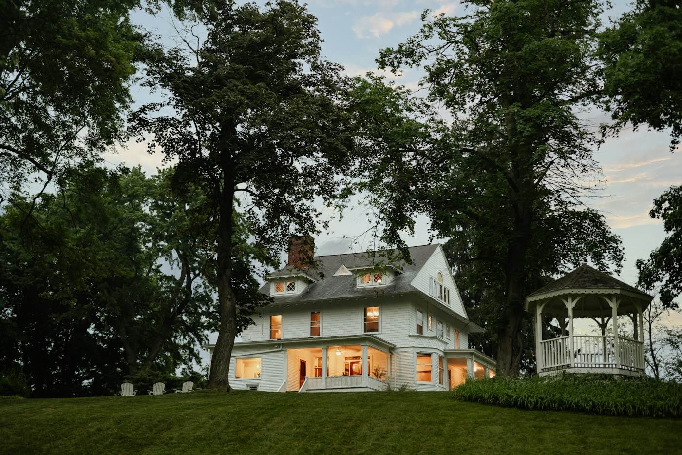 A large house with warm interior lights on at dusk