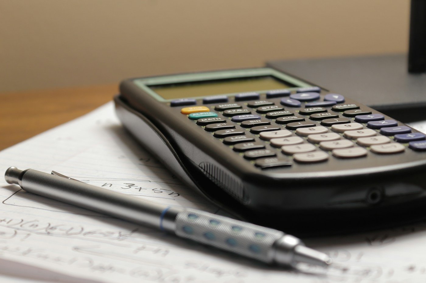 A calculator and mechanical pencil resting on handwritten notes