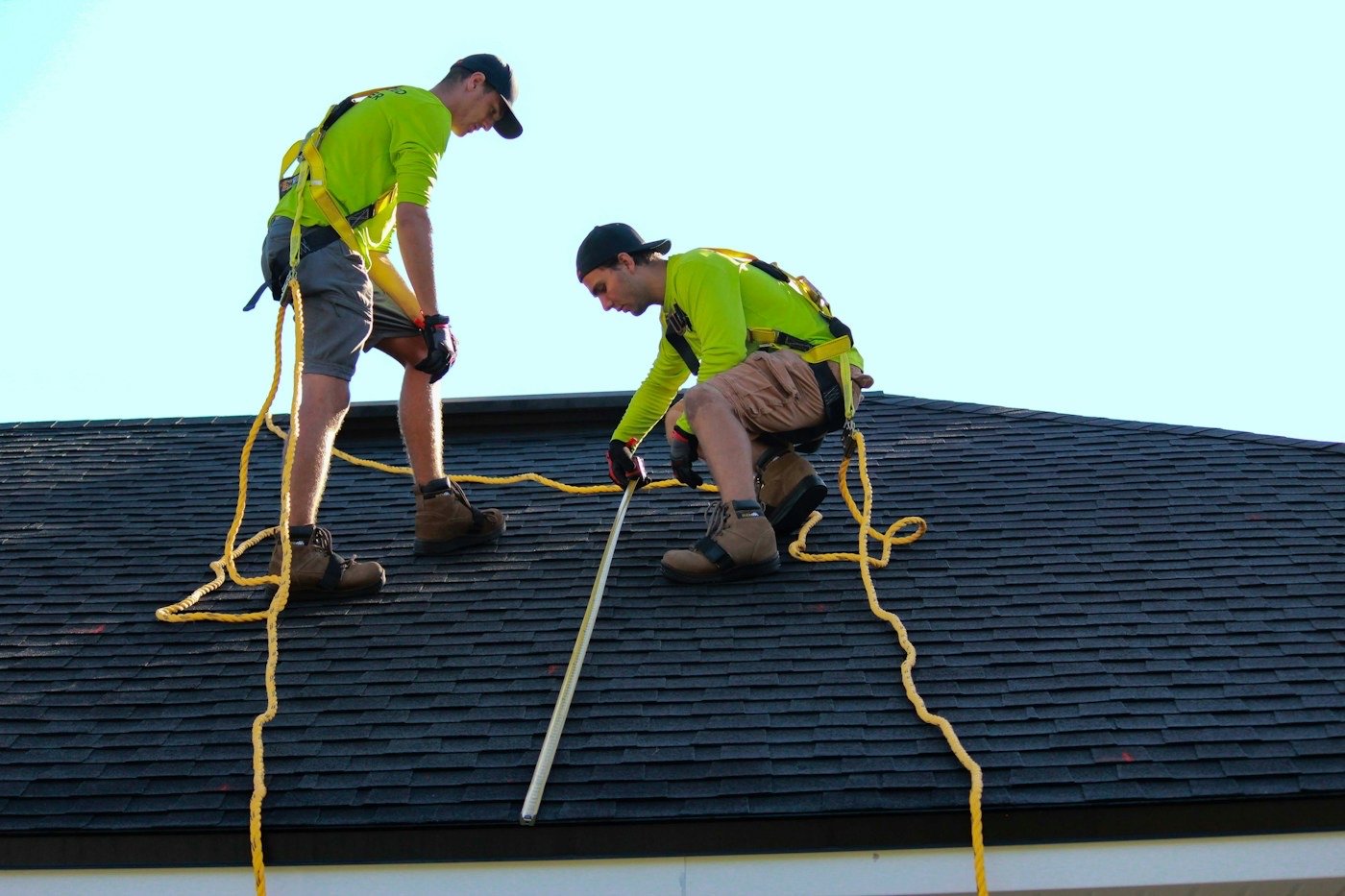 Two roofers measuring and fitting shingles on a roof