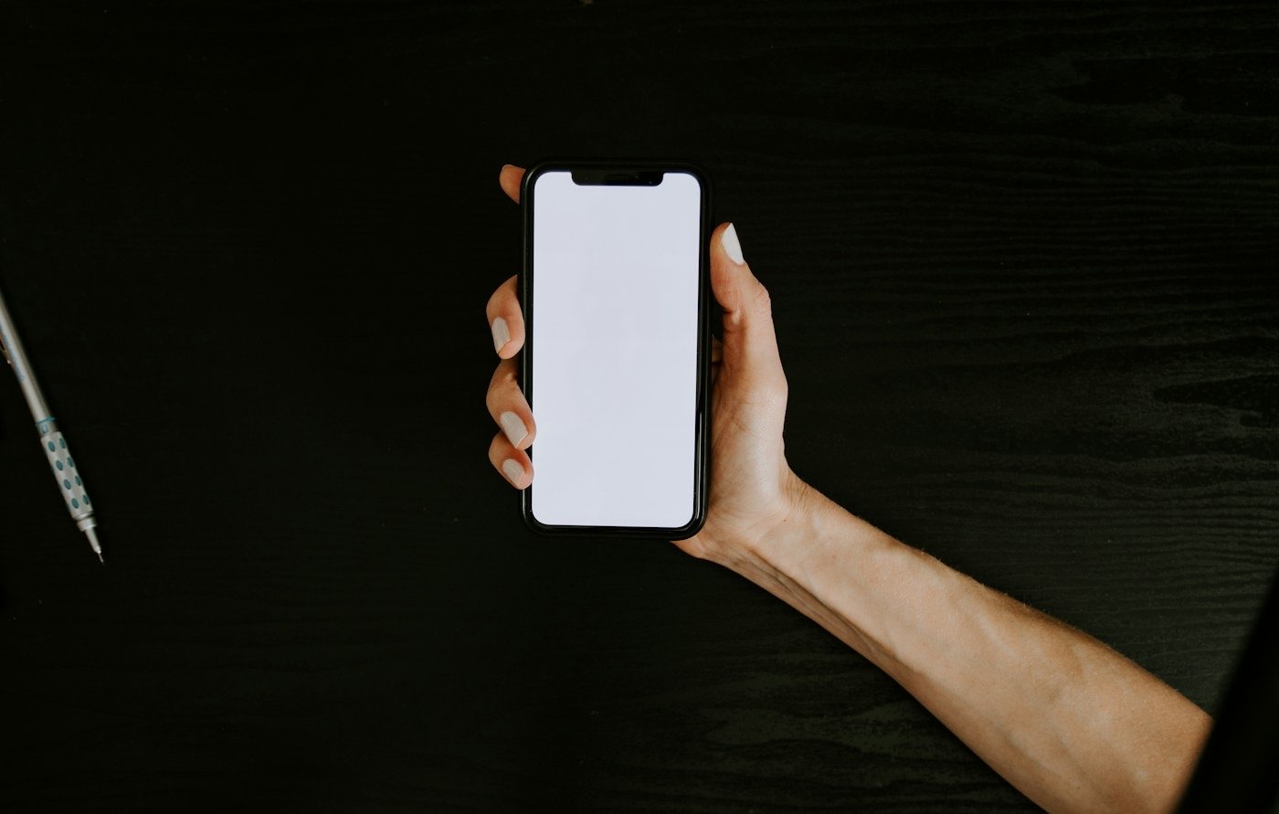 A hand holding a phone with a blank white screen