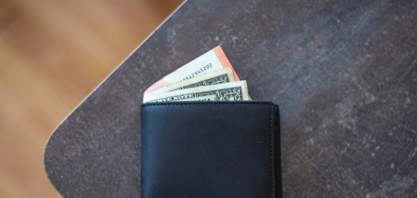 A plain black wallet with cash tucked inside